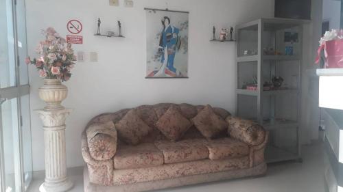 a living room with a couch and a vase of flowers at Hospedaje Harjeny in Trujillo