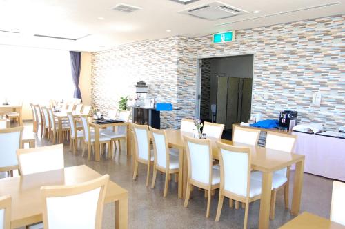 a dining room with tables and white chairs at Seagrande Shimizu Station Hotel in Shizuoka