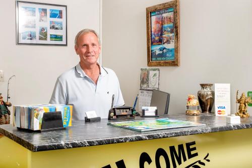 a man standing in front of a counter at Tourist Court Motel in Whakatane