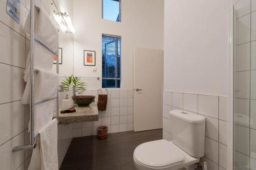 a white bathroom with a toilet and a sink at Stone Store Lodge in Kerikeri