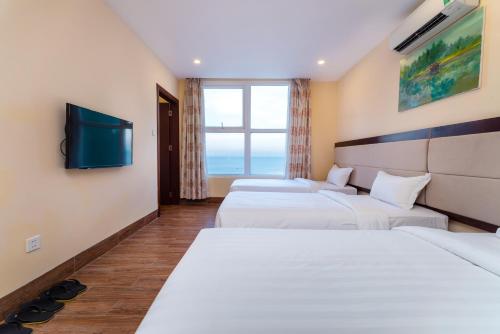 a hotel room with three beds and a flat screen tv at Nhat Minh Hotel and Apartment in Da Nang