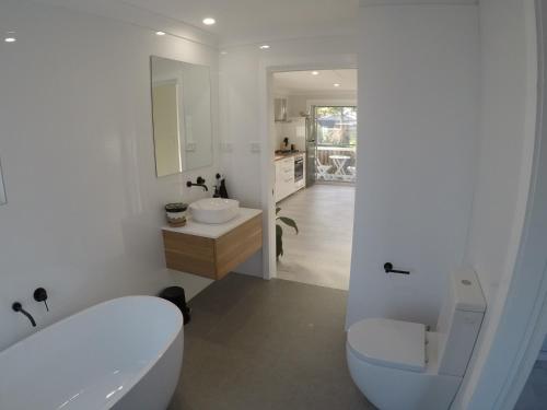 a bathroom with a tub and a toilet and a sink at Lautan Cronulla Beach in Cronulla