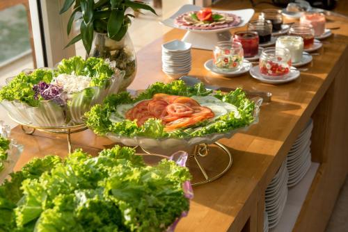 a table filled with lettuce and vegetables on a table at Nhat Minh Hotel and Apartment in Da Nang