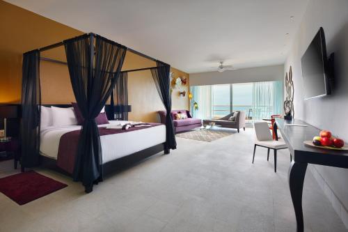 1 dormitorio con cama con dosel y sala de estar. en Senses Riviera Maya - Oceanfront All inclusive Boutique hotel - Adults only, en Puerto Morelos