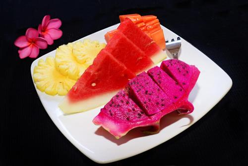 a white plate with three slices of fruit on it at Mama Bella's Retreat in Senggigi 