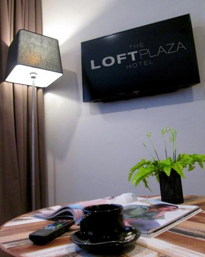 a table with a lamp and a tv on the wall at The Loft Plaza Hotel in Bangi