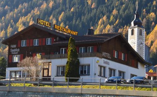 a hotel in front of a mountain with a church at Hotel Seeblick in Sufers