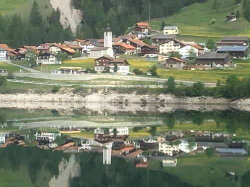a small town with a reflection in a body of water at Hotel Seeblick in Sufers