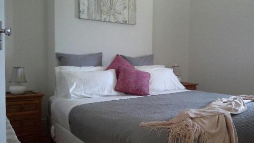 a bedroom with a bed with purple and white pillows at Book Keepers Cottage in Waikerie