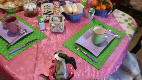 a table with a pink table cloth with plates and cups at SA SPENDULA B&B in Villacidro