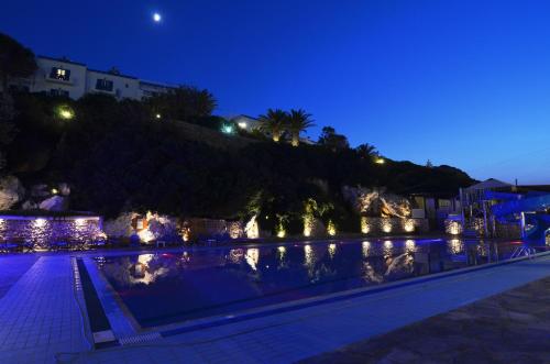 a swimming pool lit up at night with lights at Dolphin Bay Seaside Resort & Suites in Galissas