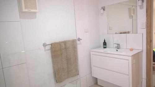 a white bathroom with a sink and a shower at Book Keepers Cottage in Waikerie