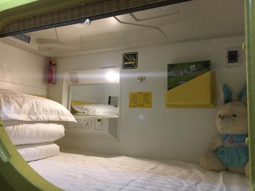 a room with a bed with a teddy bear next to a mirror at Wuwei Qiyou Space Capsule Hostel in Wuwei