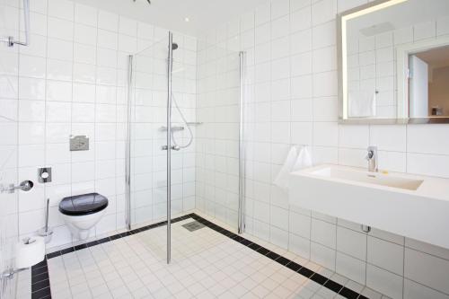 a bathroom with a shower and a toilet and a sink at Thon Hotel Opera in Oslo