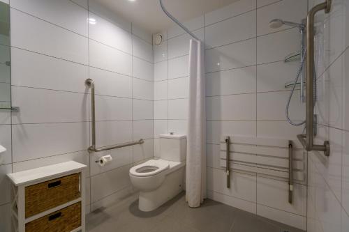 a white bathroom with a toilet and a shower at Apartments 118 in Christchurch
