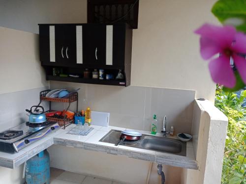a kitchen counter with a sink and a stove at Twins Homestay in Canggu