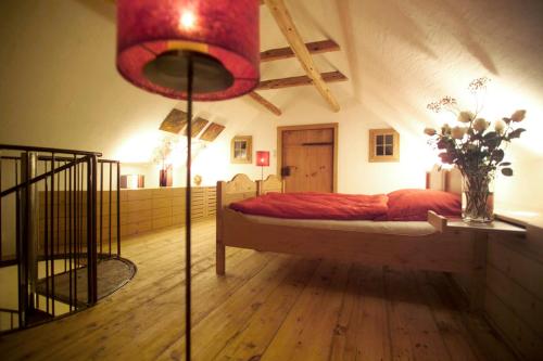 1 dormitorio con 1 cama con sábanas rojas y un jarrón de flores en Ferienhaus Troadkasten - Familie Friedrich, en Hartberg