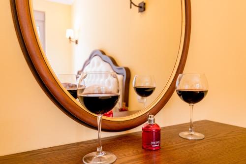 three glasses of red wine sitting on a table in front of a mirror at Apartments Magic Sea View in Kotor