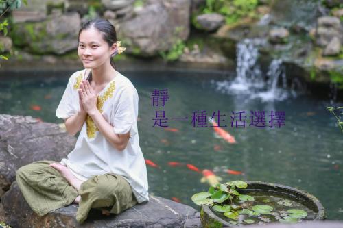 a woman sitting on a rock in front of a pond at Memory Garden in Luodong