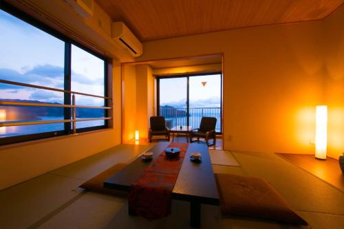 a living room with a table and large windows at Ofunato Onsen in Ōfunato