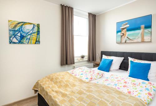 ein Schlafzimmer mit einem Bett mit blauen Kissen und einem Fenster in der Unterkunft Ferienresidenz "Seelust" Whg 5 in Waren (Müritz)