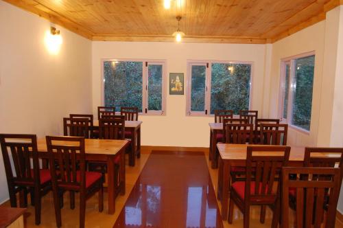 a dining room with wooden tables and chairs at Altius Nest Hotel in Kodaikānāl