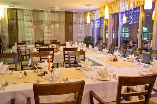 uma sala de jantar com mesas e cadeiras com toalhas de mesa brancas em Hotel Bela Krajina em Metlika