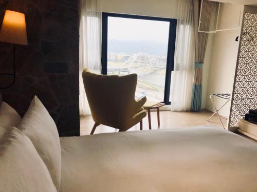 a bedroom with a bed and a chair and a window at NK Hostel in Taipei