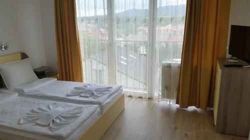 a bedroom with a bed and a large window at The Sea Lions Guest House in Tsarevo