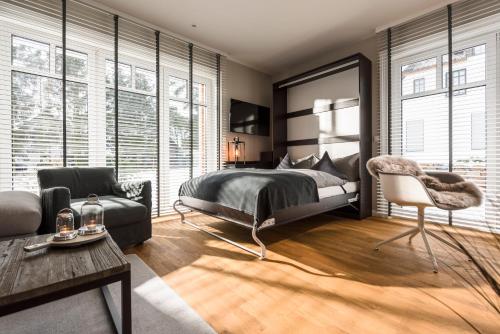 um quarto com uma cama, uma cadeira e janelas em Kamphof Usedom Ferienanlage em Loddin