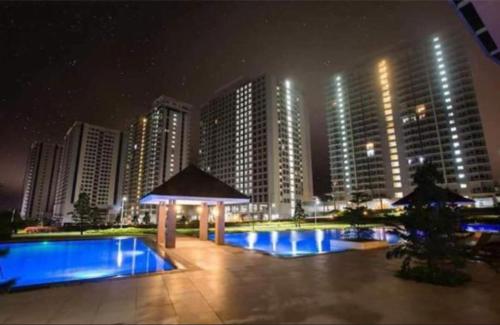 einem Pool mit Pavillon und Gebäuden in der Nacht in der Unterkunft Elizabeth 1830 @ Wind Residences in Tagaytay