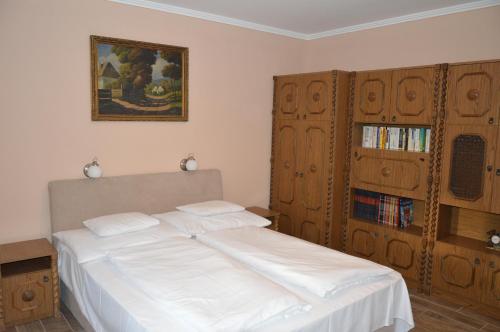a bedroom with a large white bed and wooden cabinets at Varga Apartman Hévíz in Hévíz