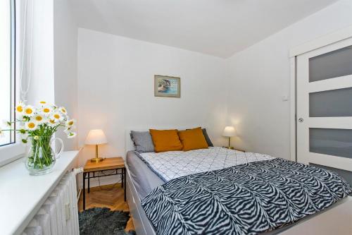 a bedroom with a bed and a vase of flowers at Sunny Suite in Center of Sopot in Sopot