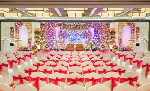 a banquet hall with red and white chairs and lights at The Residency Towers Coimbatore in Coimbatore