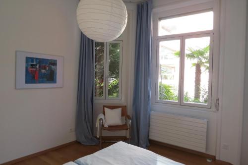 ein Schlafzimmer mit einem Bett, einem Stuhl und einem Fenster in der Unterkunft Paracelsus Locarno Stadt Wohnung in Locarno