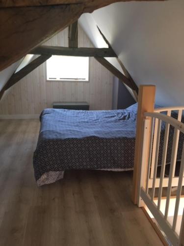Una habitación abuhardillada con una cama y una escalera. en Le petit paradis, en Daumeray