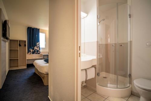 uma casa de banho com um chuveiro, um lavatório e um WC. em Ace Hôtel Clermont Ferrand La Pardieu em Clermont-Ferrand