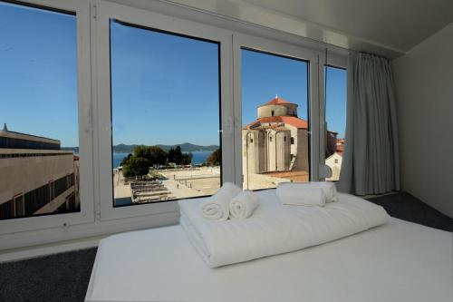 a bedroom with a white bed with a large window at Boutique Hostel Forum in Zadar