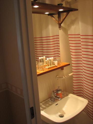 a bathroom with a white sink and a shelf at Edsleskogs Wärdshus in Åmål