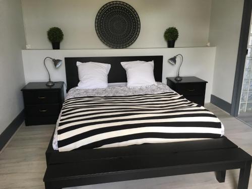 a bedroom with a black and white bed with two lamps at Appartements Le Cru Colbert in Beaune