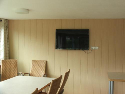 Habitación con mesa y TV en la pared. en Pension Jägerheim, en Krumbach