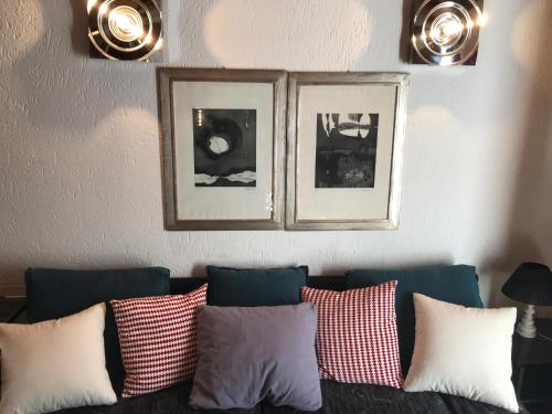 a living room with a couch with pillows and framed pictures at Hameau De Jadis in Pré-Saint-Didier