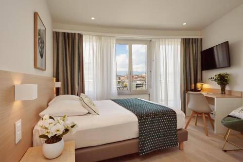 a hotel room with a bed and a desk and a window at Hotel Suisse in Geneva