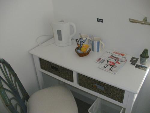 a white desk with a chair and a cup on it at La Jumelière Laval Nord in Changé