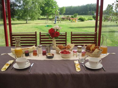 ein Tisch mit Speisen und Getränken und einem Tischtuch darauf in der Unterkunft Au Jardin Fleuri in Vauxaillon