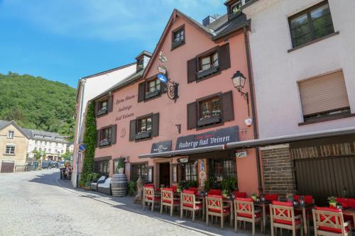 a pink building with red chairs on a street at Auberge Aal Veinen in Vianden