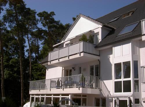 ein weißes Haus mit einem Balkon und Bäumen in der Unterkunft Fewo Strandallee - Baabe in Baabe