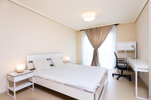 a white bedroom with a bed and a desk and a window at Vista Roja in El Médano