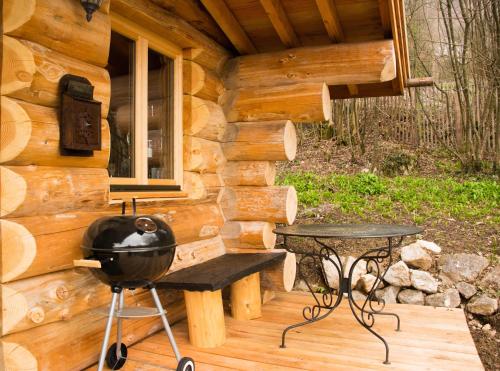 a grill and a table in front of a log cabin at Les Cabanes Du Saleve in Collonges-sous-Salève