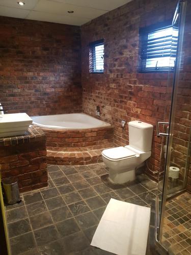 a bathroom with a tub and a toilet and a sink at City Living Boutique Hotel in Bloemfontein